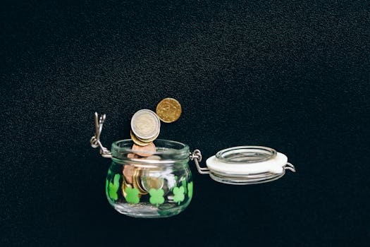 Glass jar with coins falling into it on a black background, symbolizing savings.
